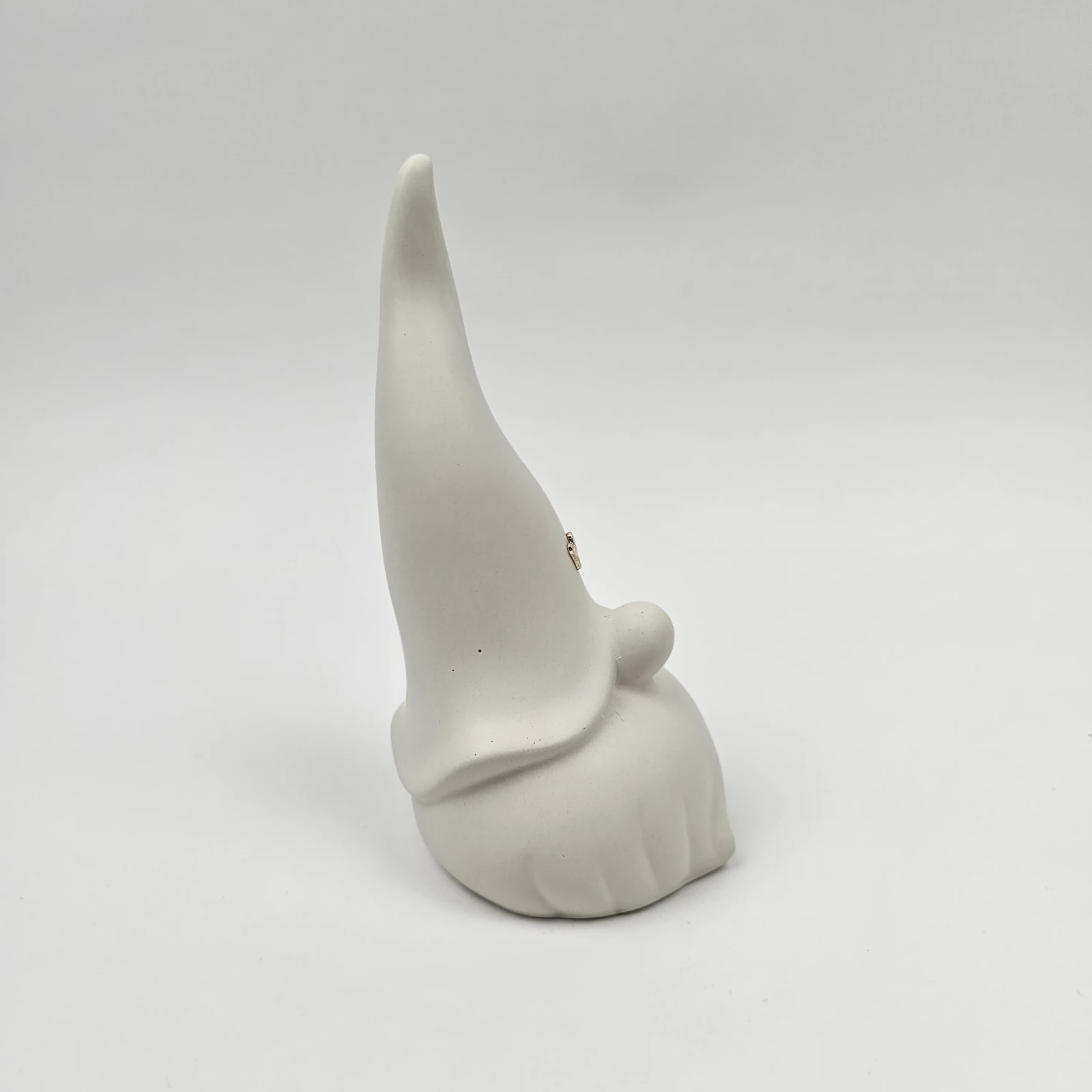 Profil białego minimalistycznego skrzata z gipsu polimerowego z wysoką, zakrzywioną czapką.