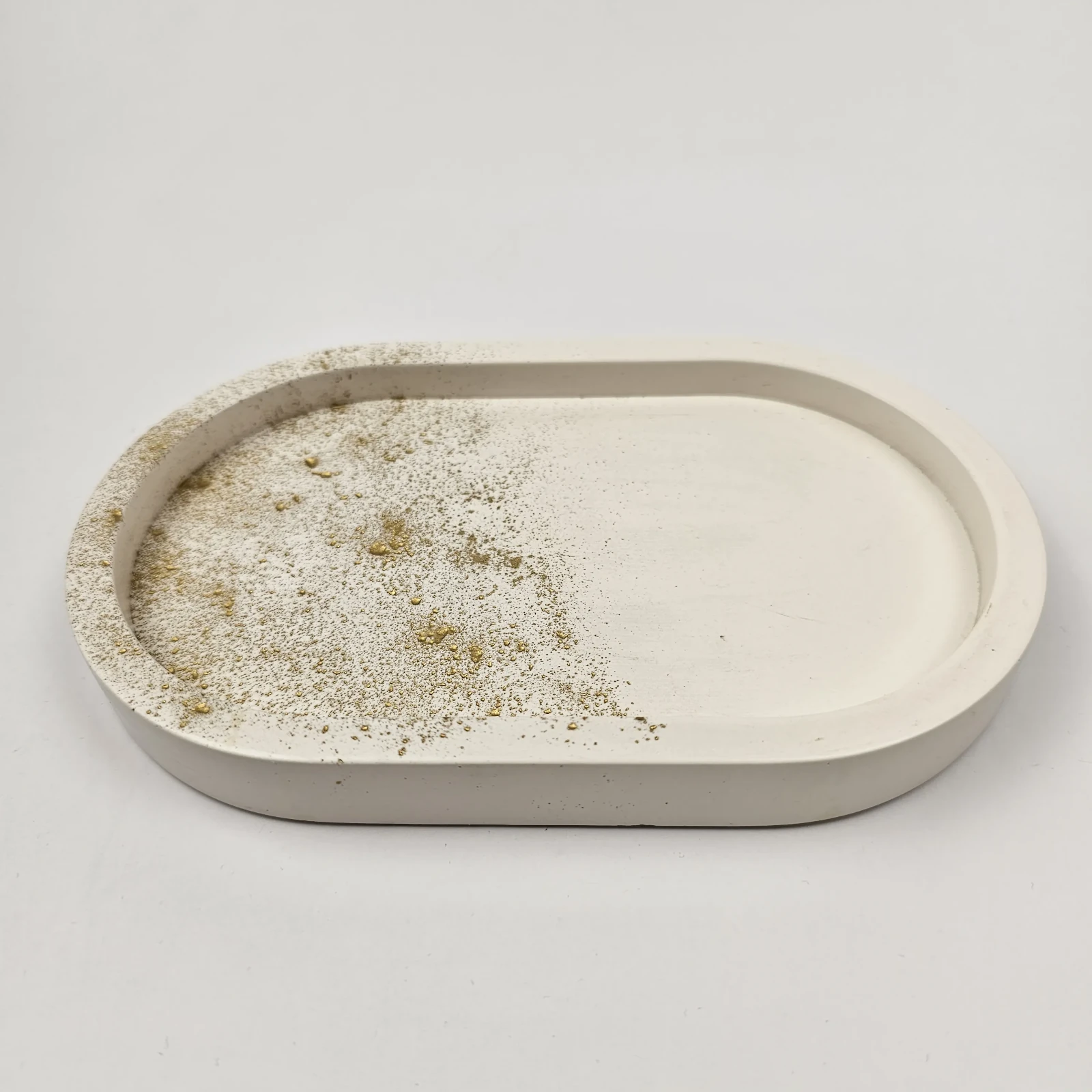 Ręcznie robiona owalna taca z gipsu polimerowego w kolorze białym ze złotym zdobieniem typu splatter, widoczny wysoki rant