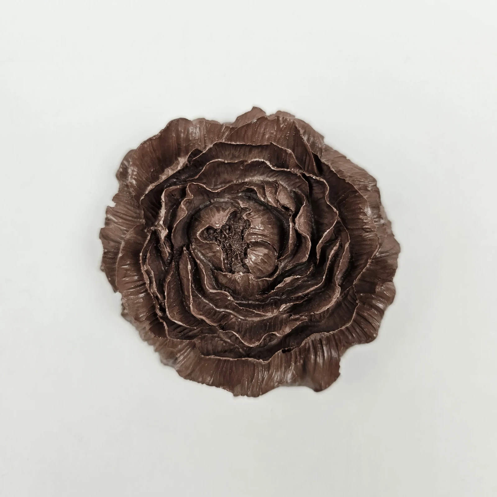 Widok z góry na symetryczną rzeźbę kwiatu peonii z gipsu polimerowego w kolorze brązowym.