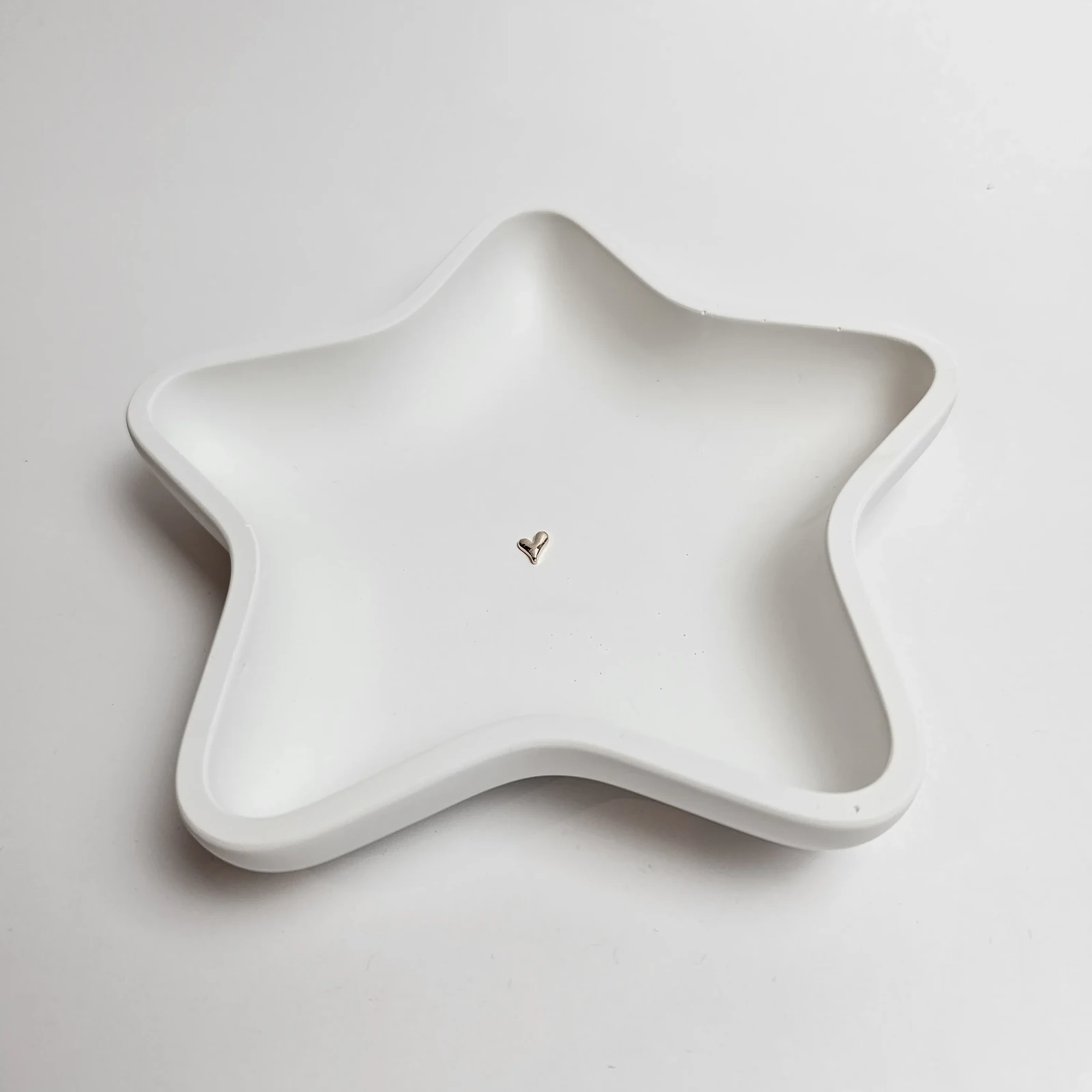 Biała ręcznie robiona podstawka w kształcie gwiazdy z gipsu polimerowego ze srebrnym serduszkiem na biżuterię.
