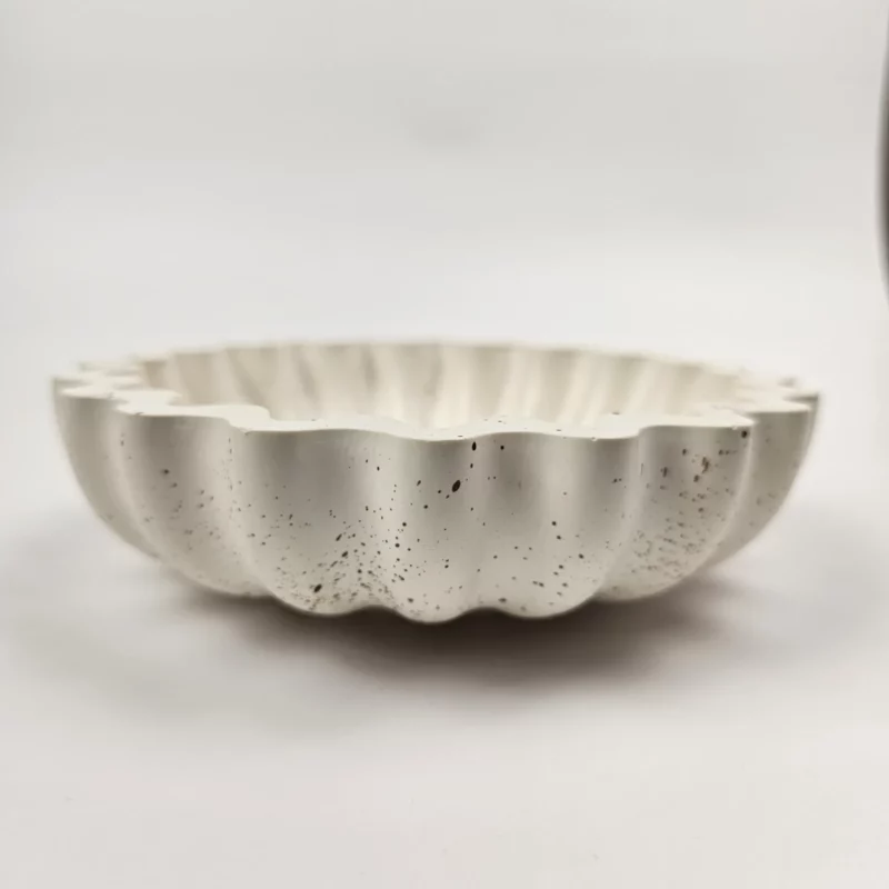 Profil ręcznie wykonanej, płytkiej miseczki ozdobnej z gipsu polimerowego, prezentującej pofałdowany kształt muszli.