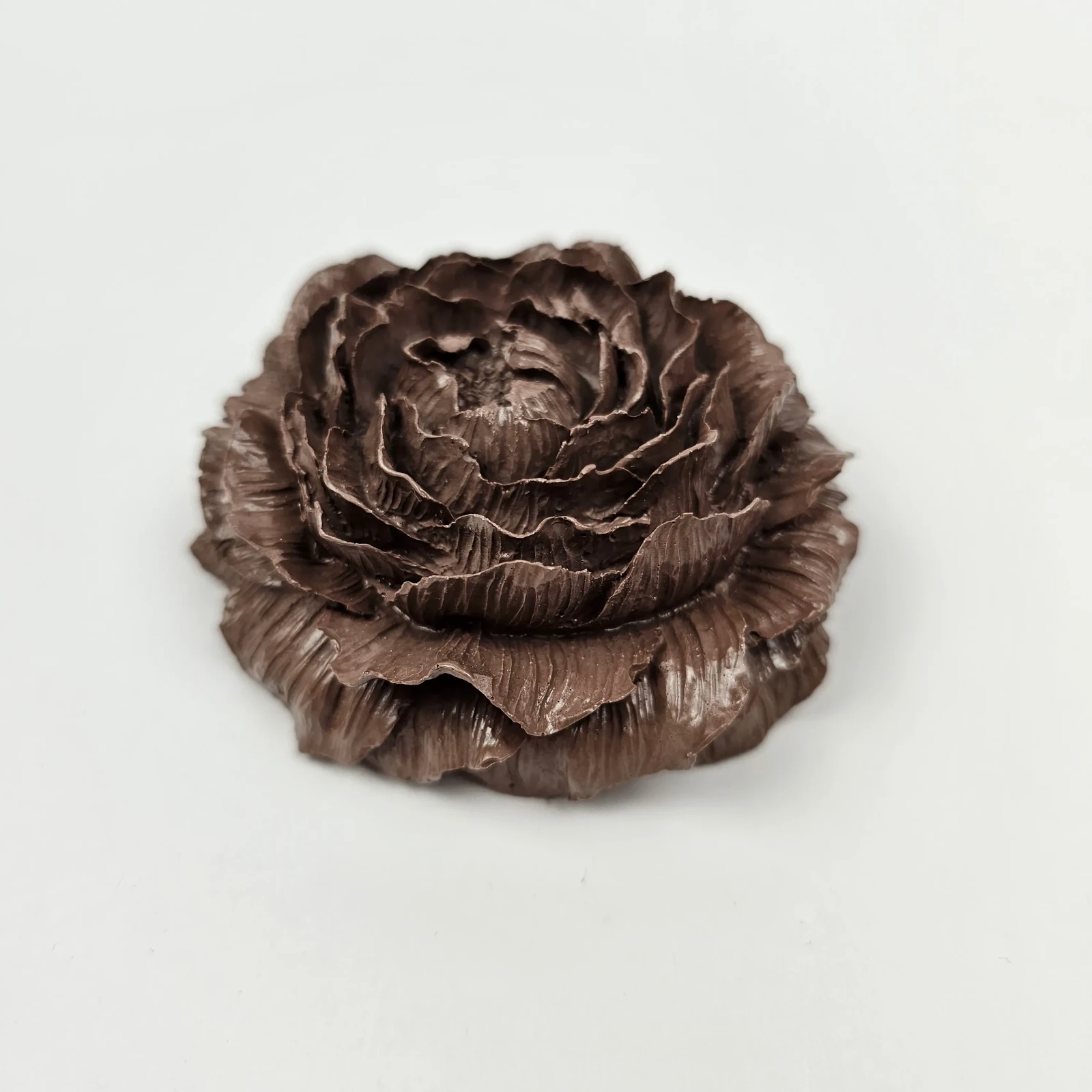 Ręcznie robiona dekoracyjna peonia z gipsu polimerowego w kolorze ciemnej czekolady, widok z boku ukazujący detale płatków.