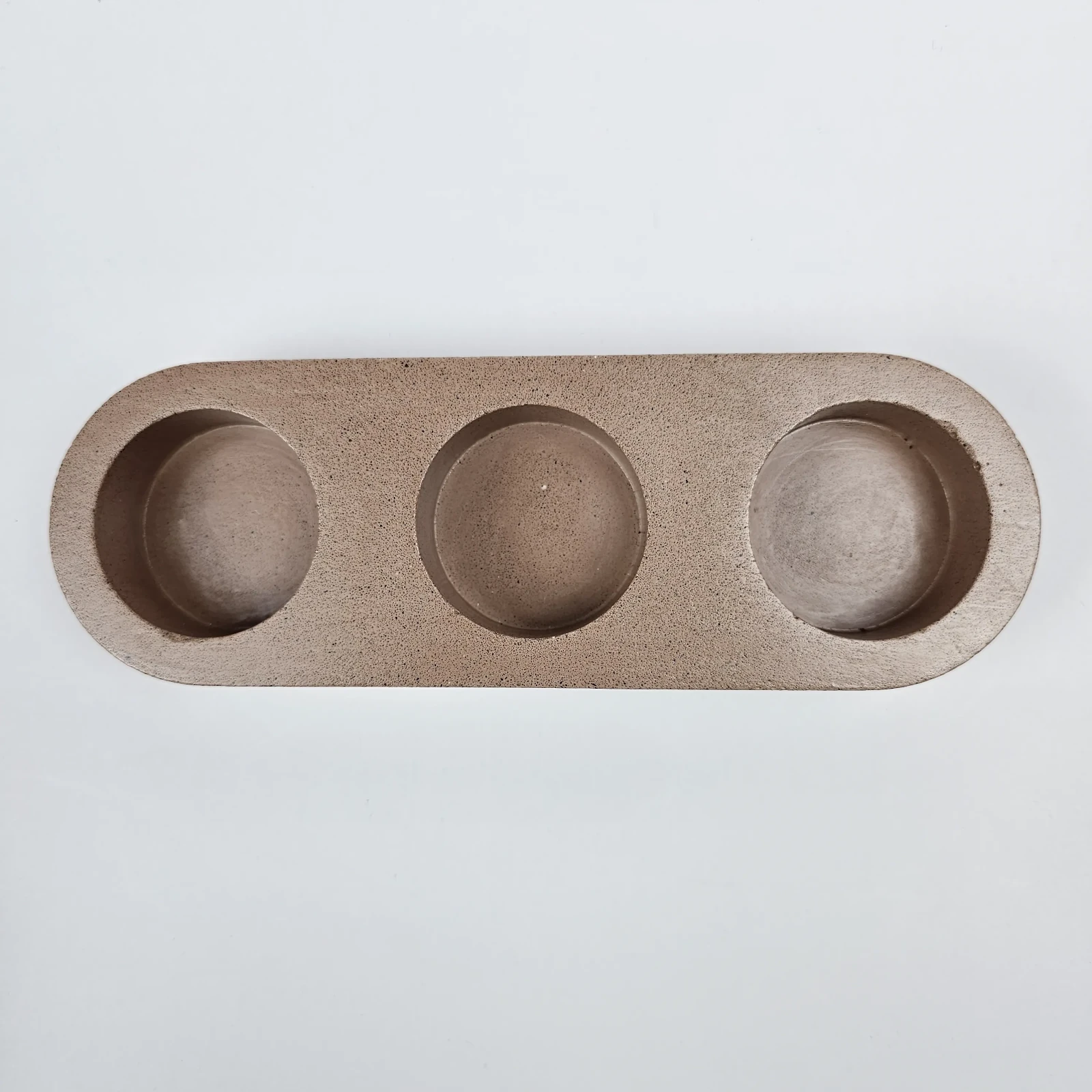 Owalna beżowa podstawka na 3 świeczki typu tealight, wykonana z trwałego gipsu polimerowego.