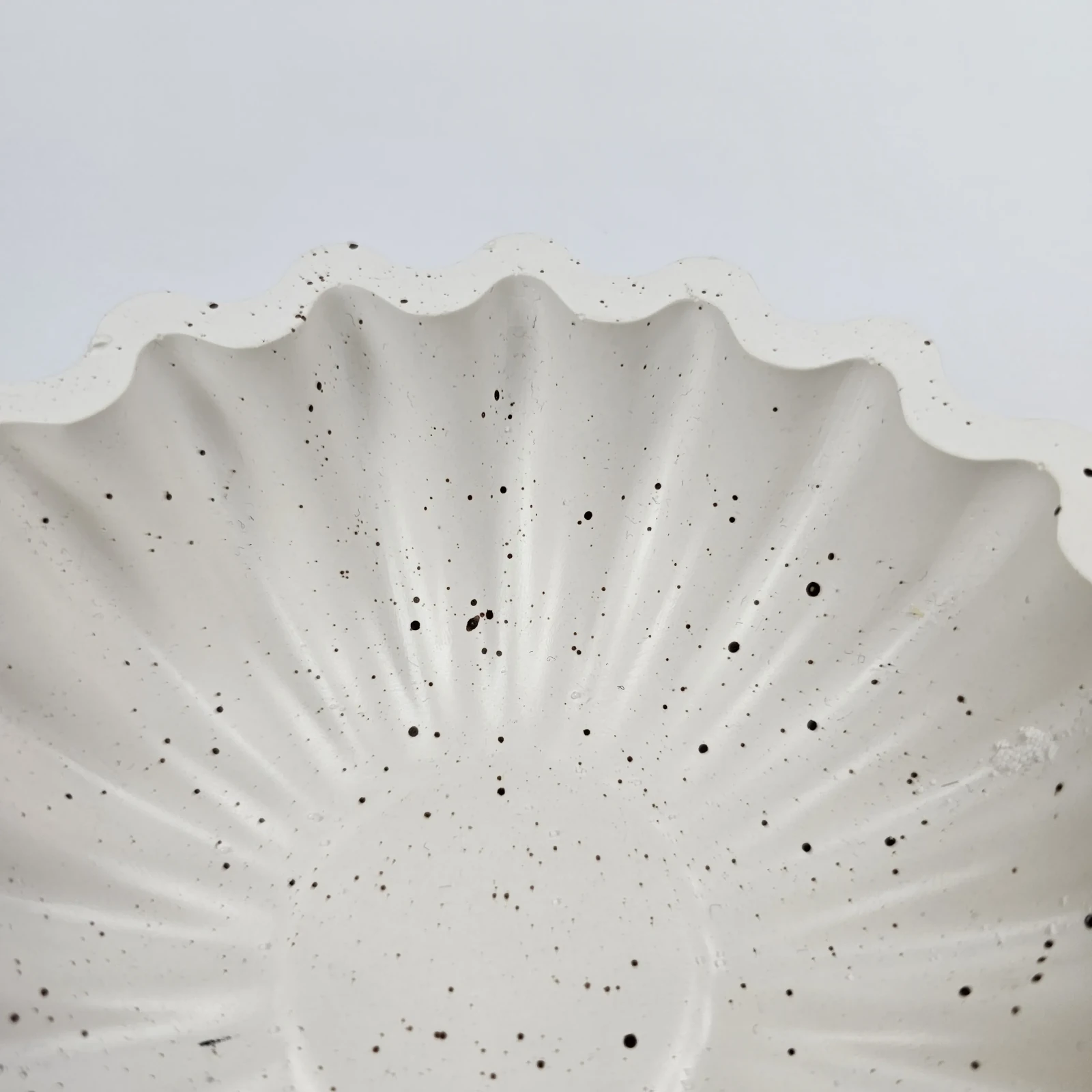 Ręcznie robiona taca dekoracyjna z ekologicznego gipsu polimerowego w kształcie muszli, widok z bliska na wzór terazzo.