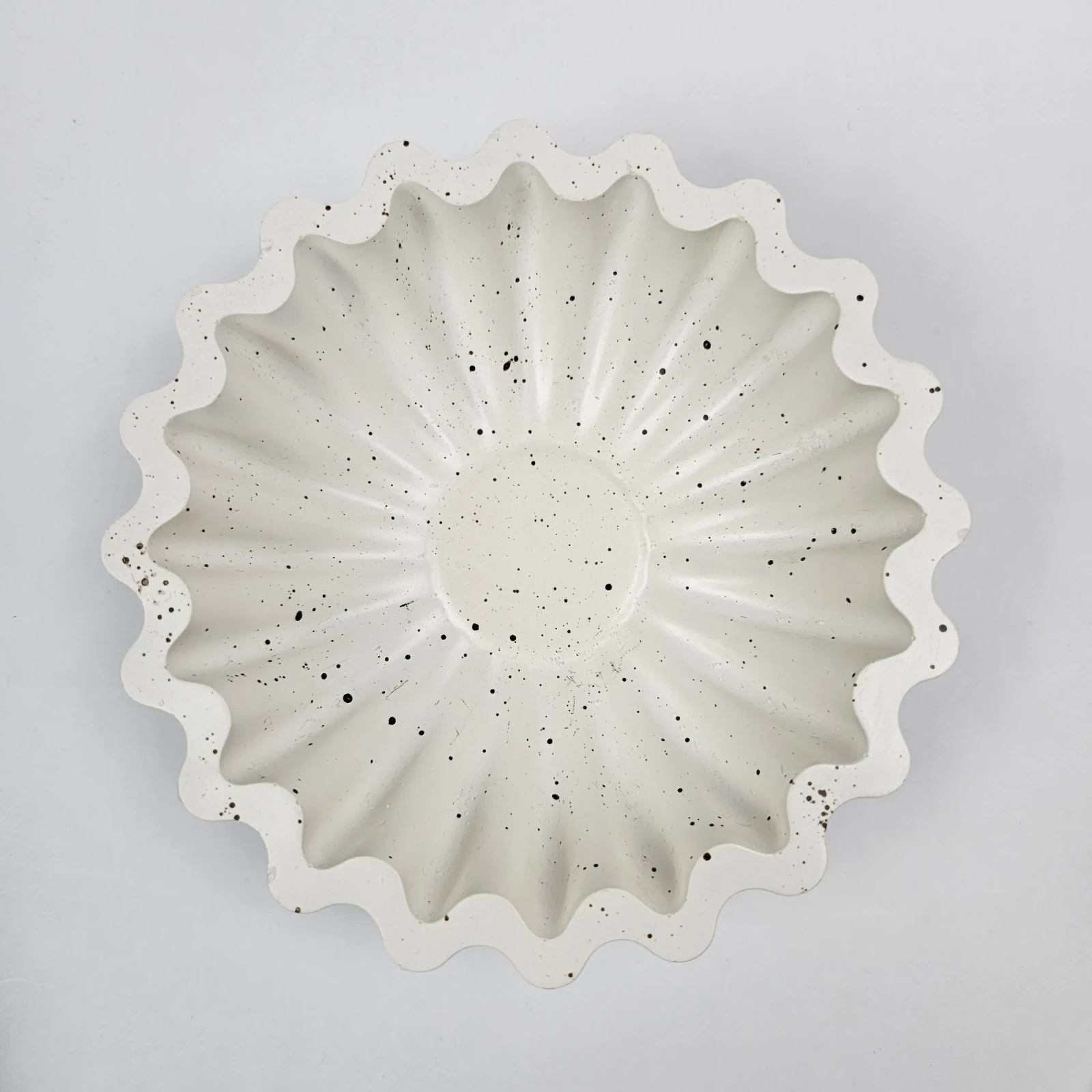 Widok z góry na okrągłą, ręcznie robioną tacę z gipsu polimerowego w stylu lastryko, przeznaczoną do przechowywania biżuterii.