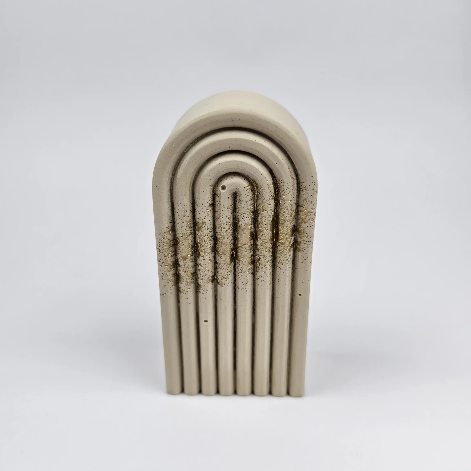 Beżowa podpórka do książek z gipsu polimerowego w kształcie tęczy ze złotym zdobieniem typu splatter.