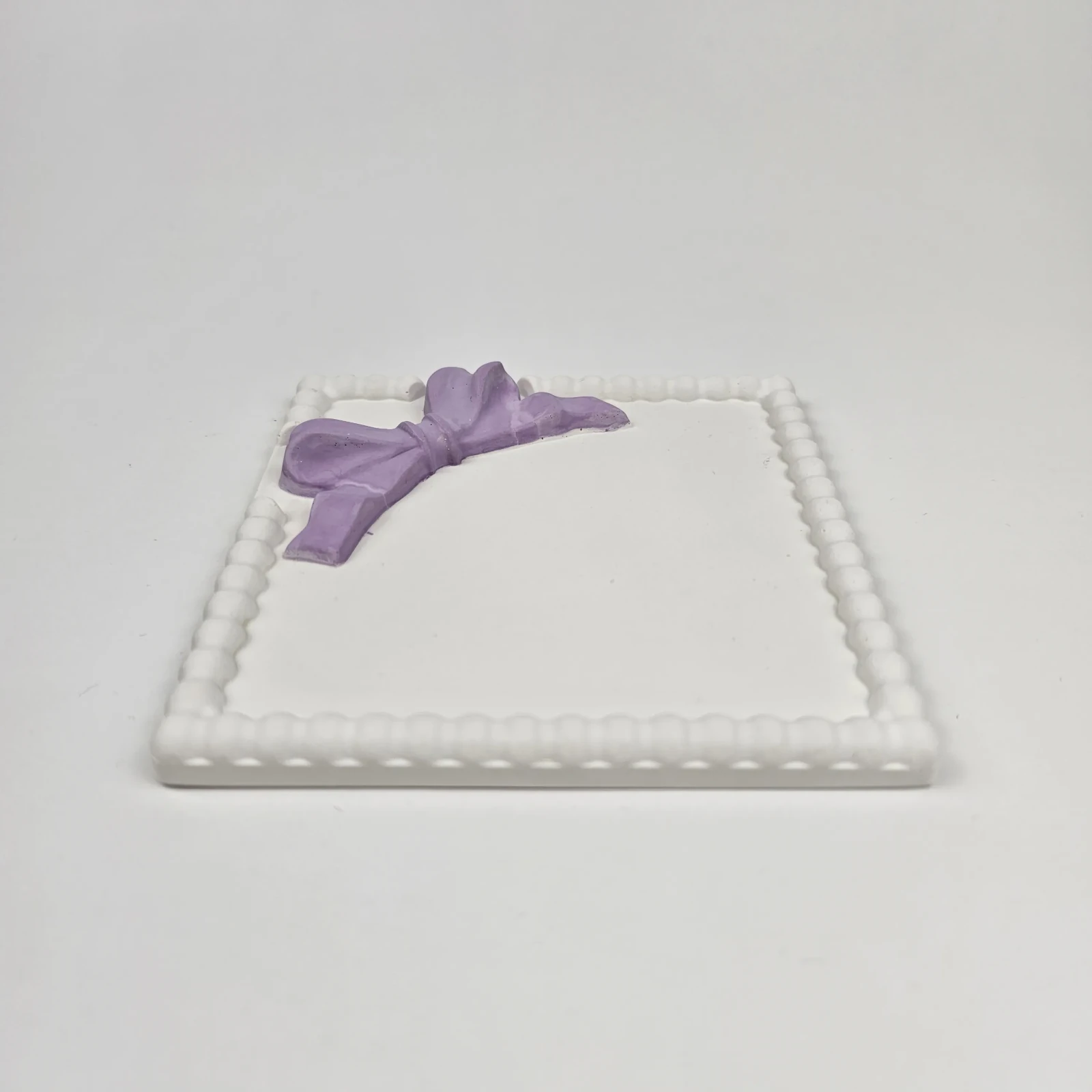 Ręcznie robiona taca na biżuterię w stylu coquette z trójwymiarową fioletową kokardą, ujęcie z boku.