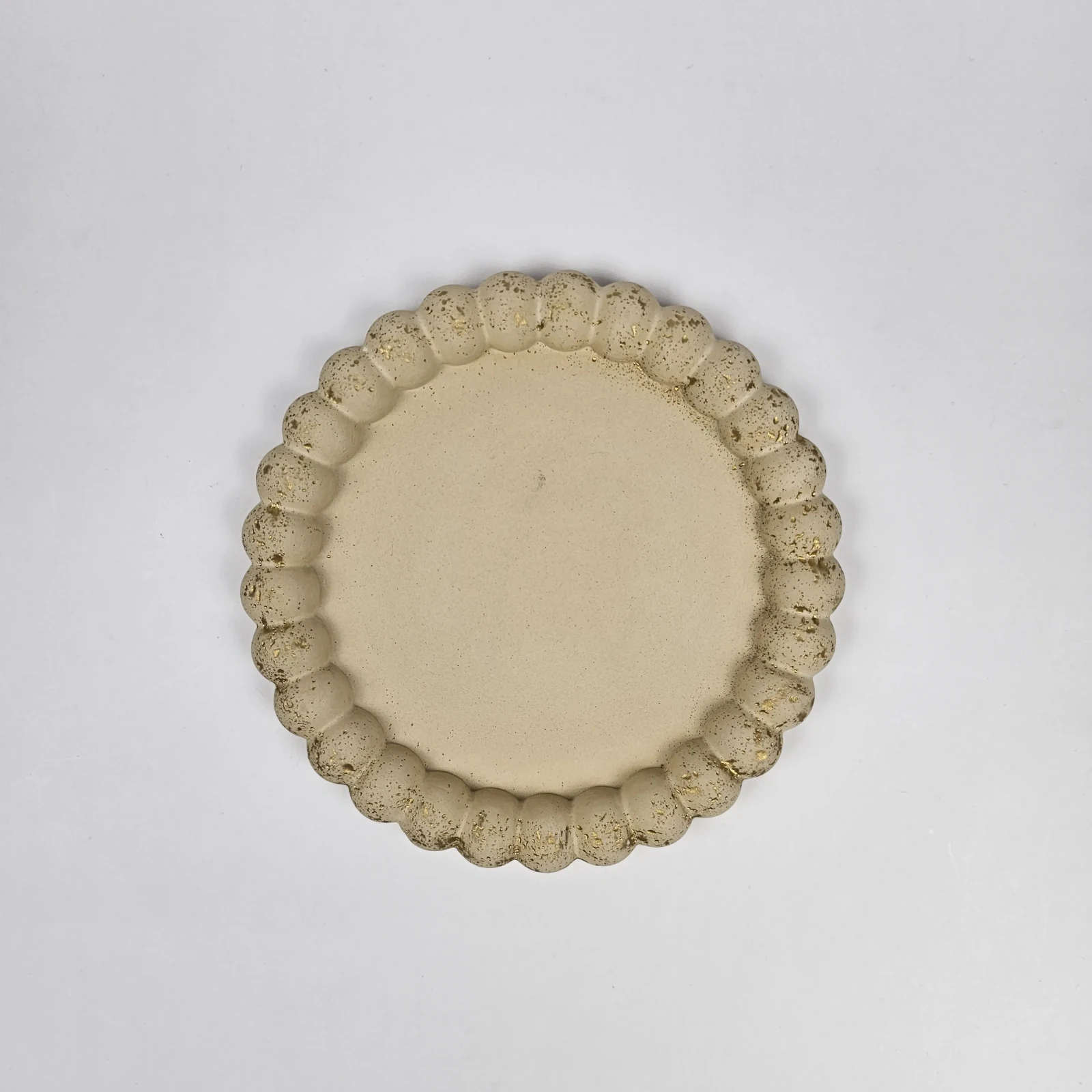 Widok z góry na beżową tackę dekoracyjną z gipsu polimerowego z rantem z kuleczek i złotym wykończeniem.