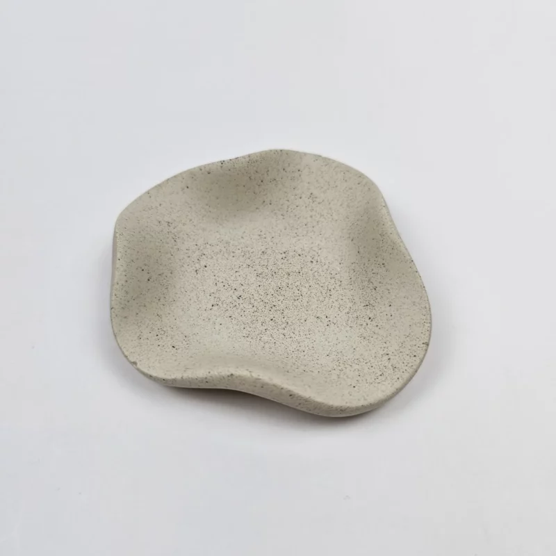 Minimalistyczna dekoracja boho z gipsu polimerowego o wykończeniu piaskowym ułożona na białym tle.