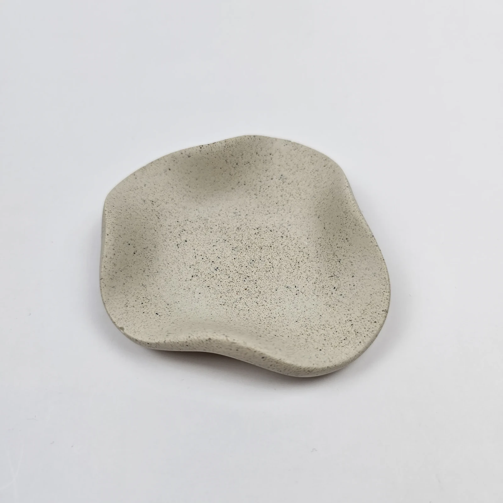 Minimalistyczna dekoracja boho z gipsu polimerowego o wykończeniu piaskowym ułożona na białym tle.