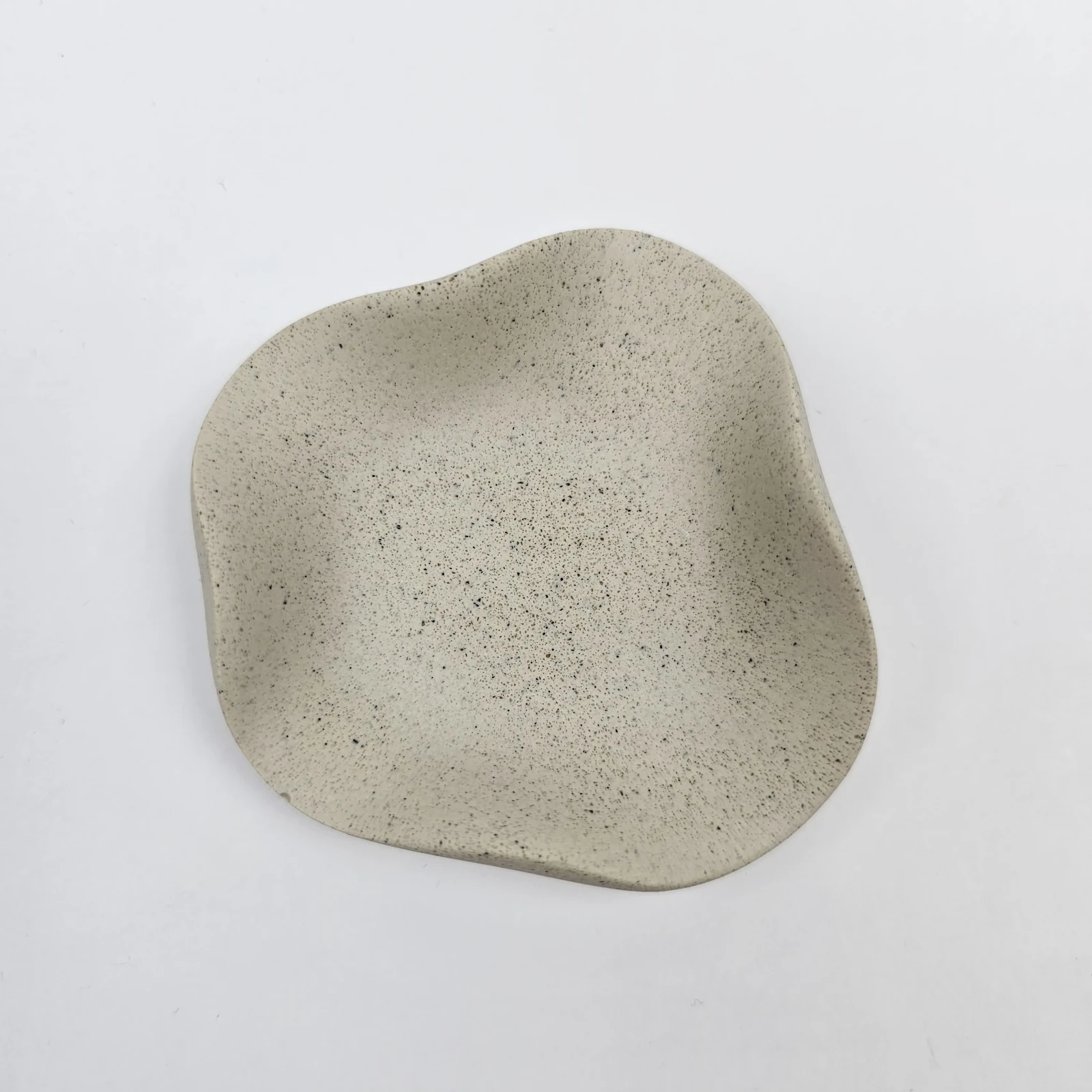 Ręcznie robiona tacka na biżuterię z gipsu polimerowego z piaskiem, widok z góry na nieregularny kształt.