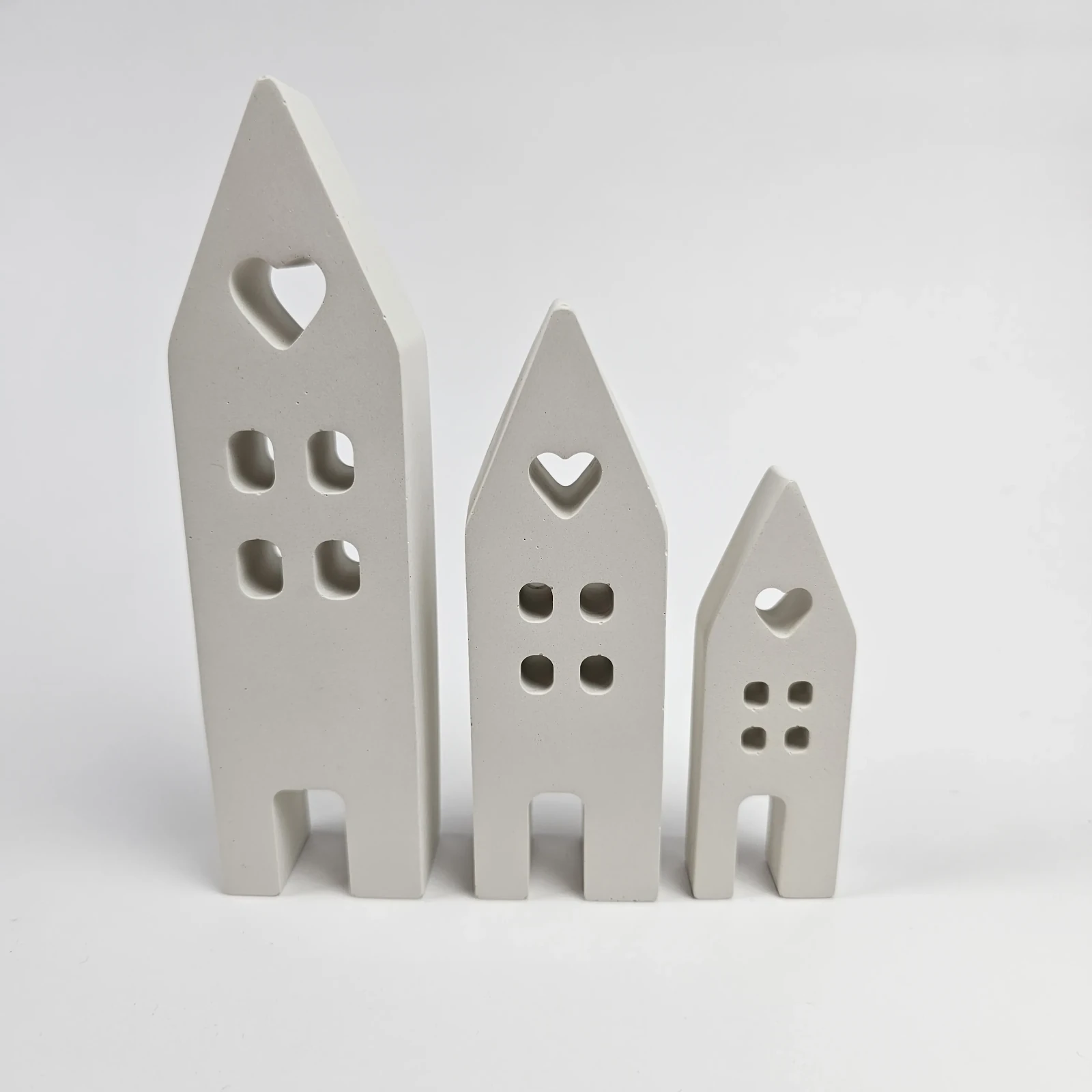 Zestaw trzech białych domków dekoracyjnych z gipsu polimerowego z motywem serca w stylu skandynawskim.
